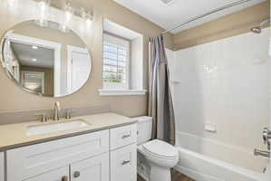 Bathroom featuring a white vanity with an undermount sink, a light-toned countertop, and a circular mirror
