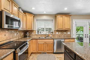 Kitchen featuring wood-finish cabinetry, granite countertops, stainless steel appliances, and tile flooring