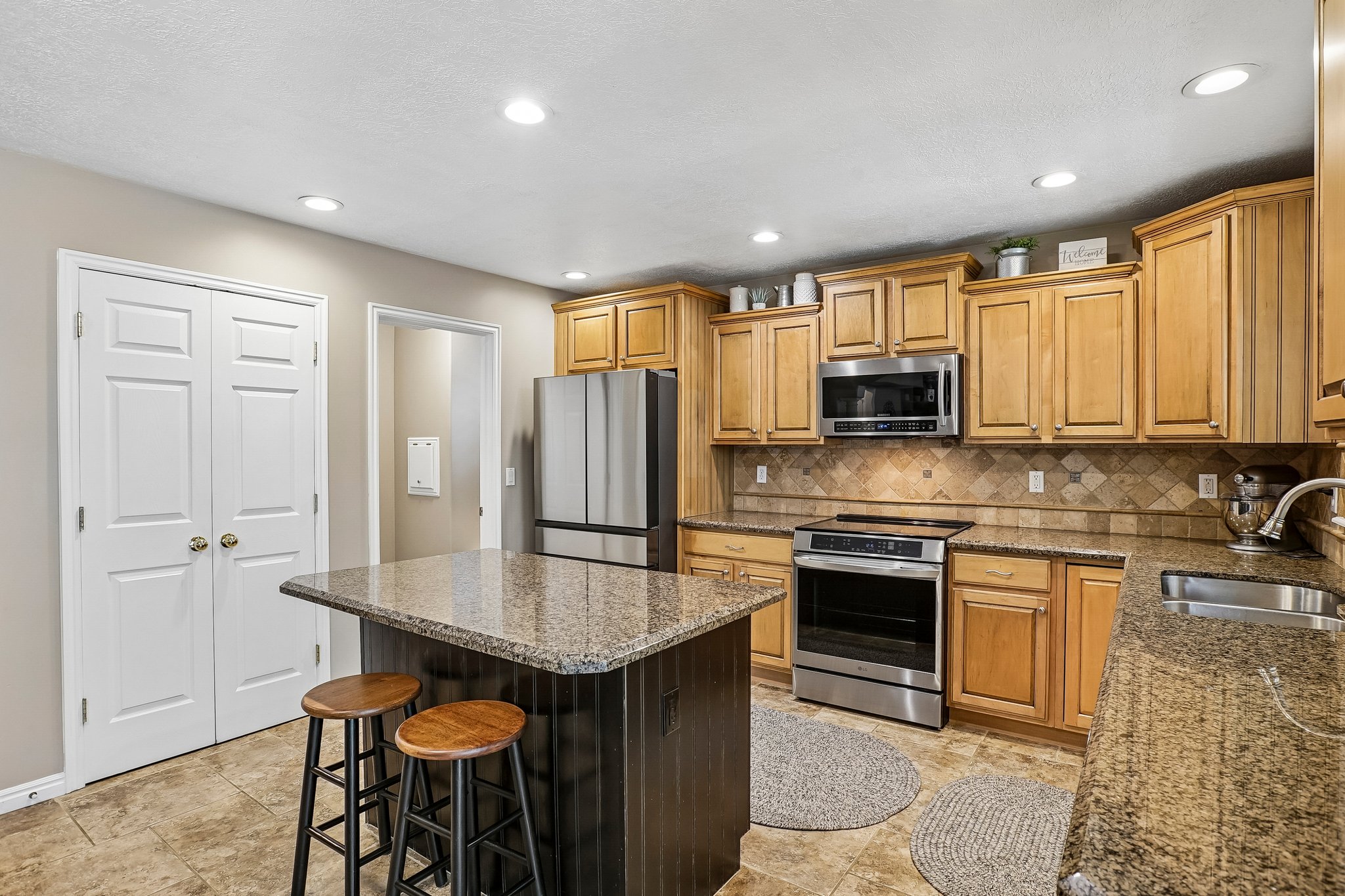 Kitchen featuring light wood cabinetry, stainless steel appliances, and a central island with a granite countertop