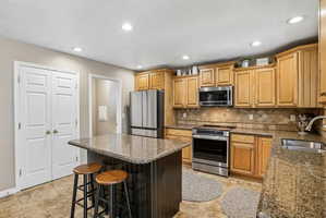Kitchen featuring light wood cabinetry, stainless steel appliances, and a central island with a granite countertop