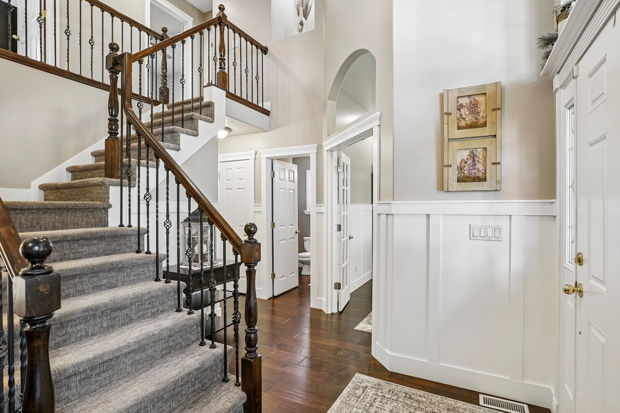 Foyer entry featuring a sweeping staircase with dark wood handrails and wrought iron balusters
