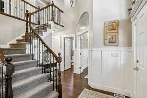 Foyer entry featuring a sweeping staircase with dark wood handrails and wrought iron balusters