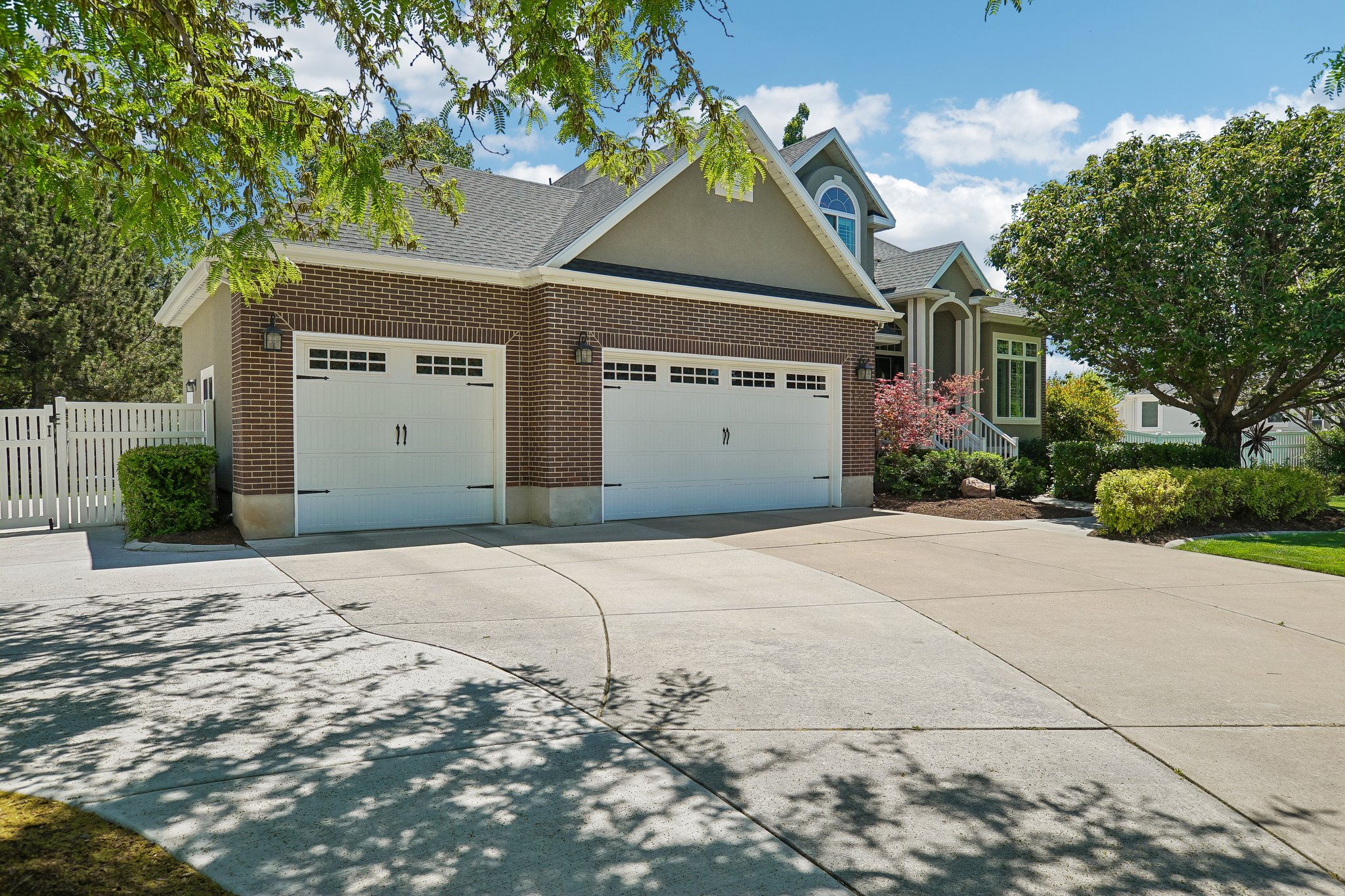 Brick and siding exterior featuring two white garage doors with decorative hardware