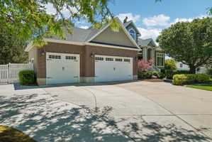 Brick and siding exterior featuring two white garage doors with decorative hardware