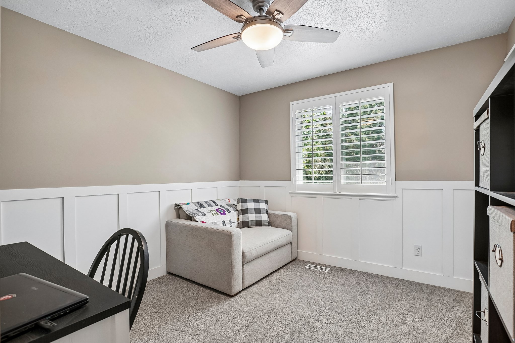 Room featuring a sloped ceiling, wood-finish ceiling fan, and board-and-batten wainscoting
