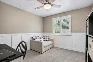 Room featuring a sloped ceiling, wood-finish ceiling fan, and board-and-batten wainscoting
