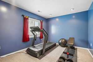Carpeted room featuring a window with white blinds and red drapes, recessed lighting, and blue painted walls