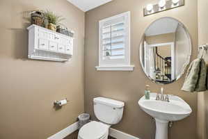 Pedestal sink with chrome fixtures, an oval mirror, and a three-light vanity bar