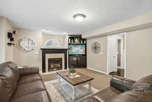 Carpeted living area featuring a fireplace with a dark wood mantel and tile surround, built-in shelving, and recessed lighting
