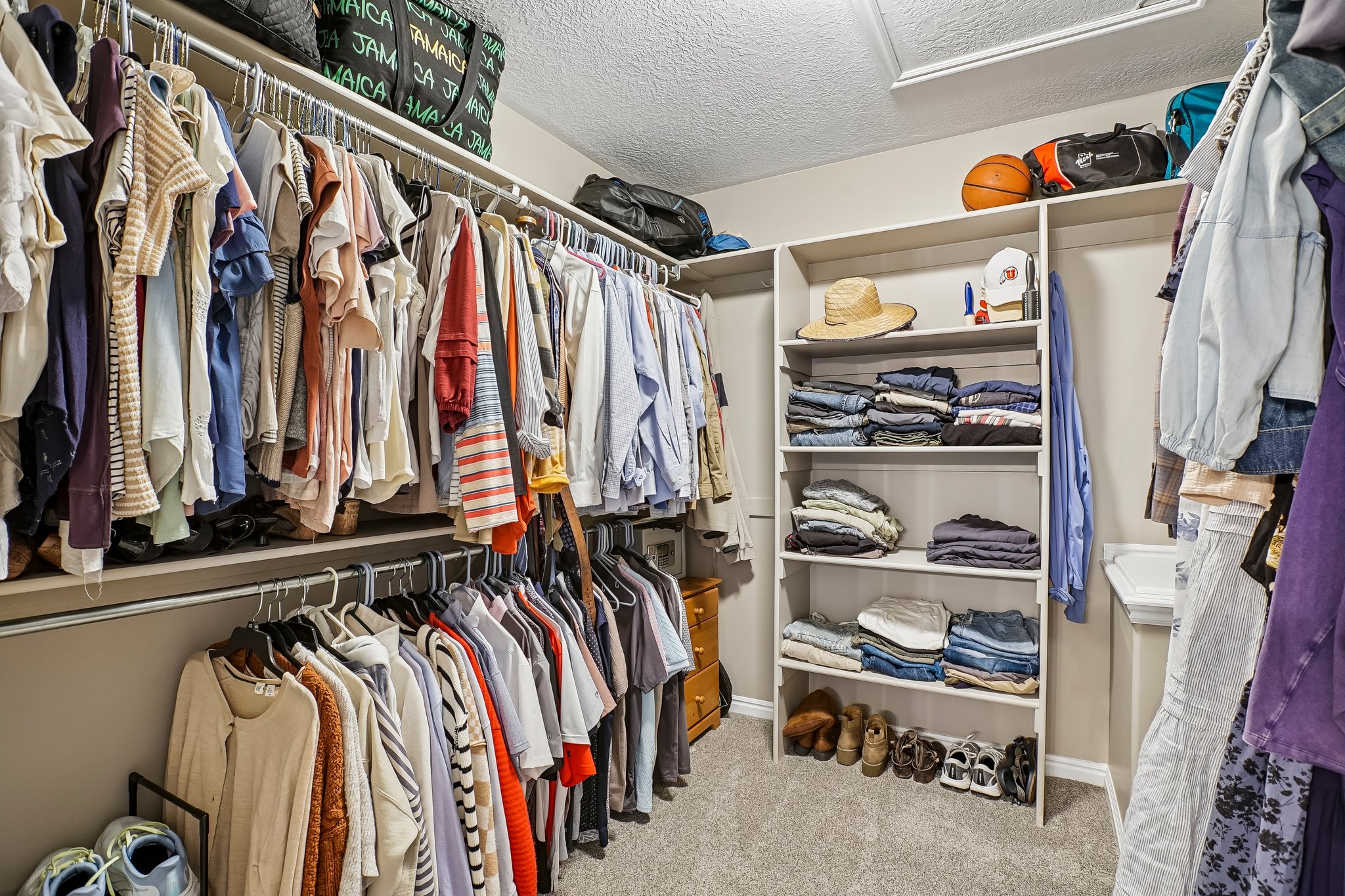 Spacious walk-in closet featuring extensive built-in shelving and multiple clothing racks
