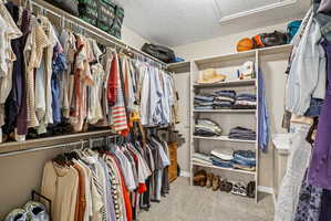 Spacious walk-in closet featuring extensive built-in shelving and multiple clothing racks