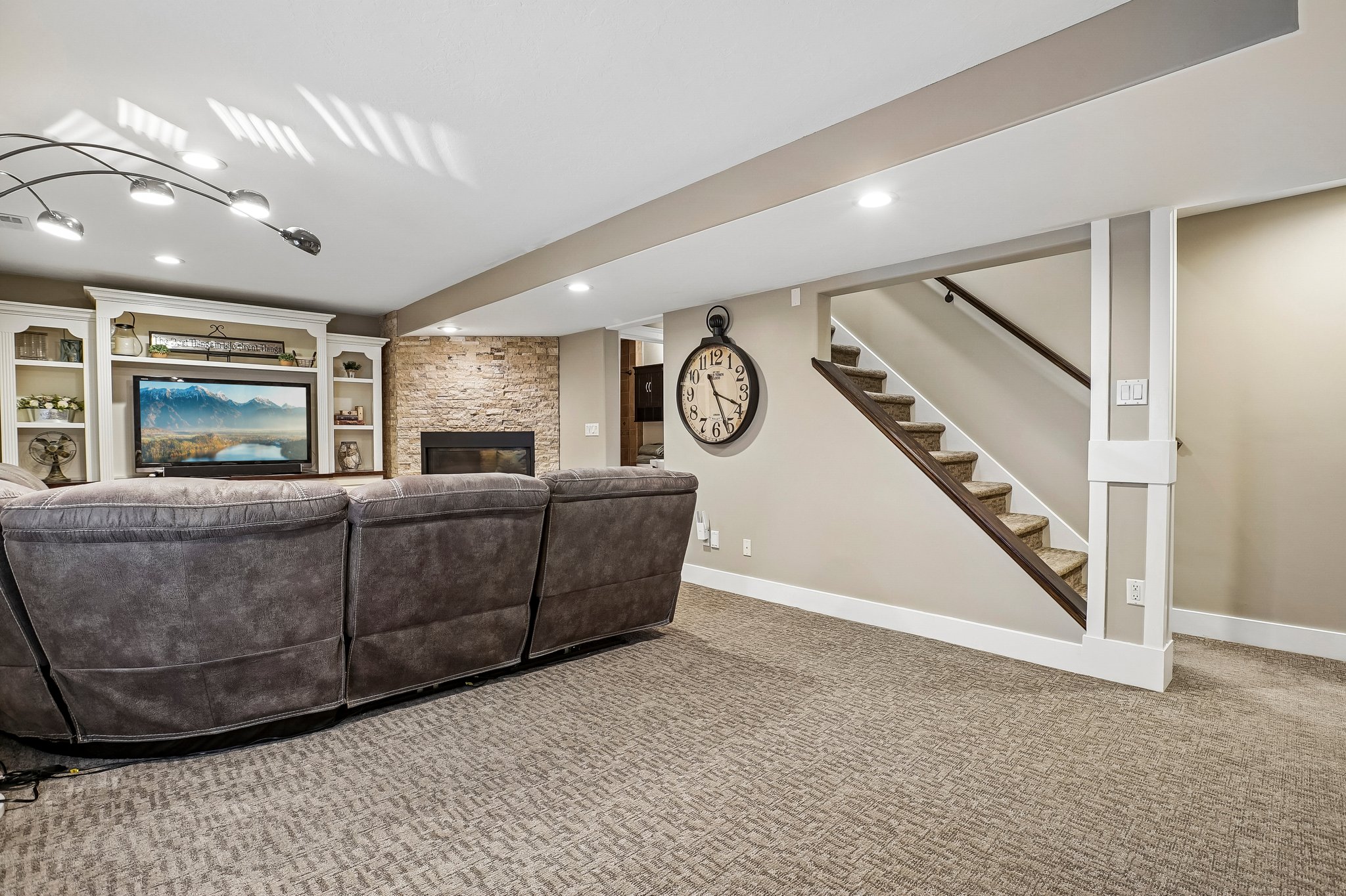 Carpeted living area featuring a stone accent wall, an integrated fireplace, and white built-in shelving