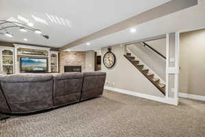 Carpeted living area featuring a stone accent wall, an integrated fireplace, and white built-in shelving