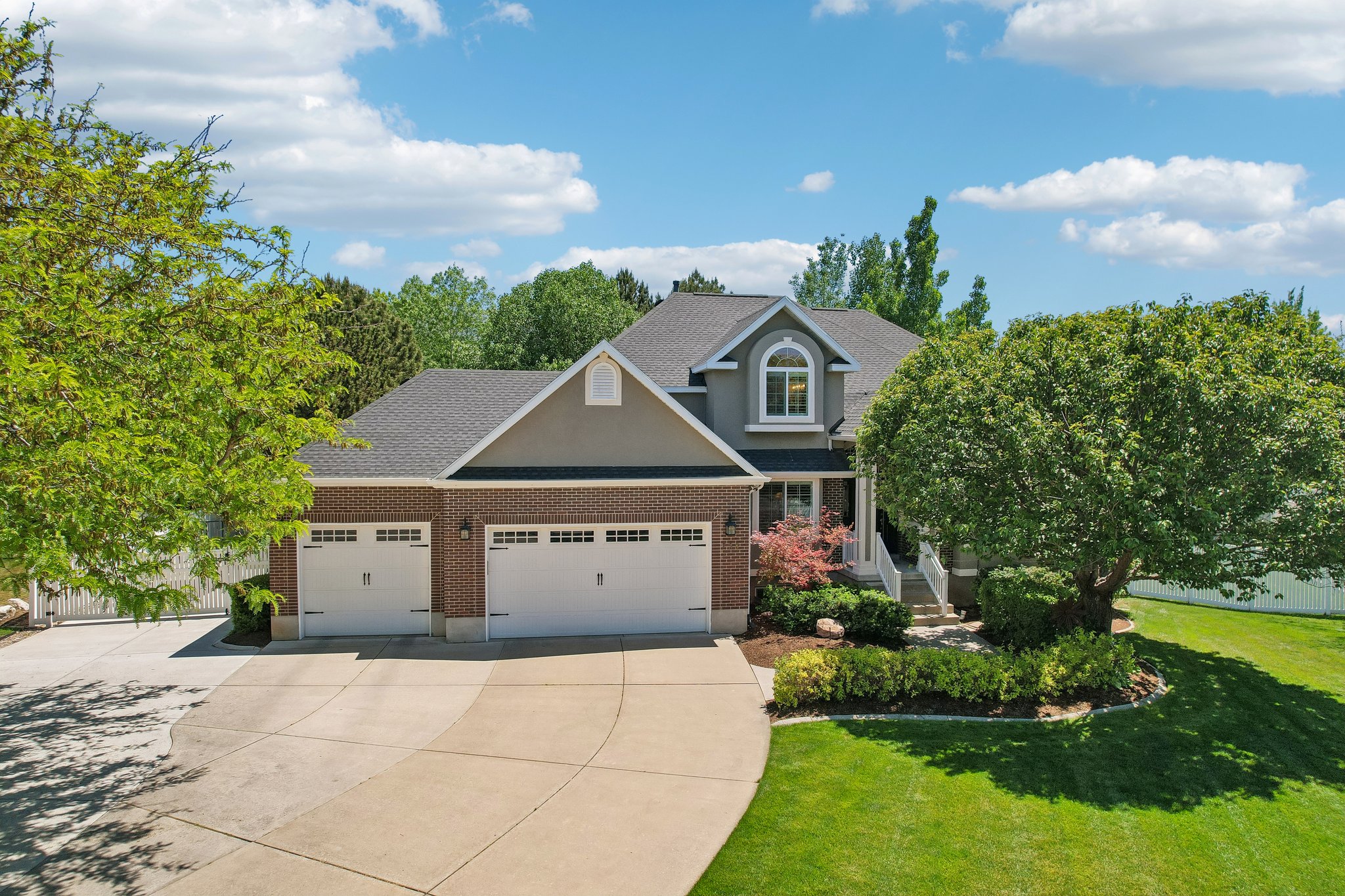 Two-story residence featuring a brick and stucco facade, a two-car garage, and a concrete driveway