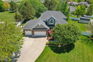 Two-story residence featuring a dark gray roof, a three-car garage, and a concrete driveway