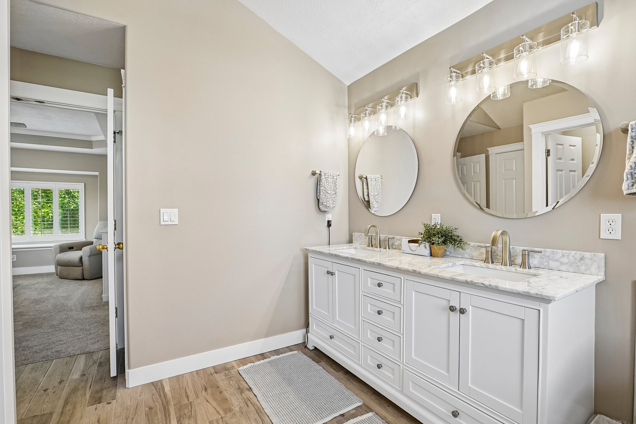 Double vanity with white cabinetry and a light-toned countertop, featuring two round mirrors and brushed nickel fixtures