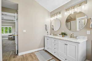 Double vanity with white cabinetry and a light-toned countertop, featuring two round mirrors and brushed nickel fixtures
