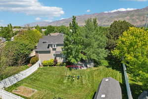 Expansive fenced backyard featuring a manicured lawn, mature trees, and a built-in garden bed