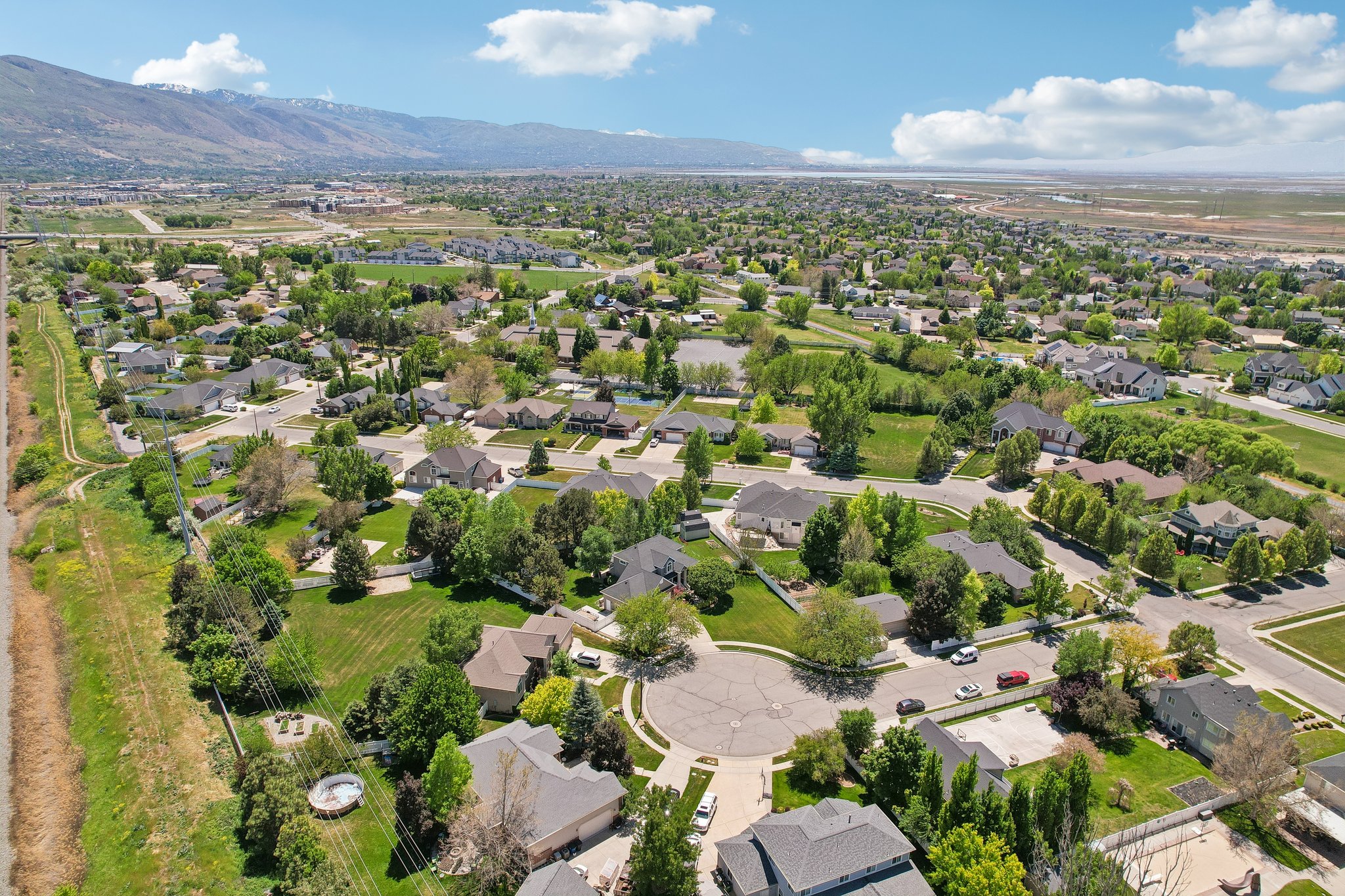 Suburban neighborhood featuring varied residential architecture, mature landscaping, and cul-de-sac streets, with a distant mountain range backdrop