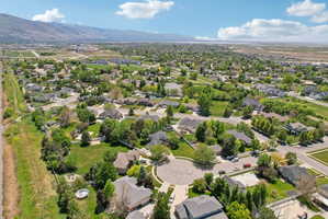 Suburban neighborhood featuring varied residential architecture, mature landscaping, and cul-de-sac streets, with a distant mountain range backdrop