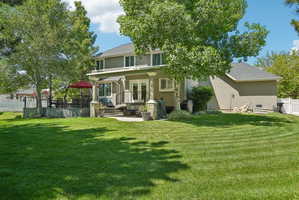 Expansive green lawn with mature trees and a multi-level patio