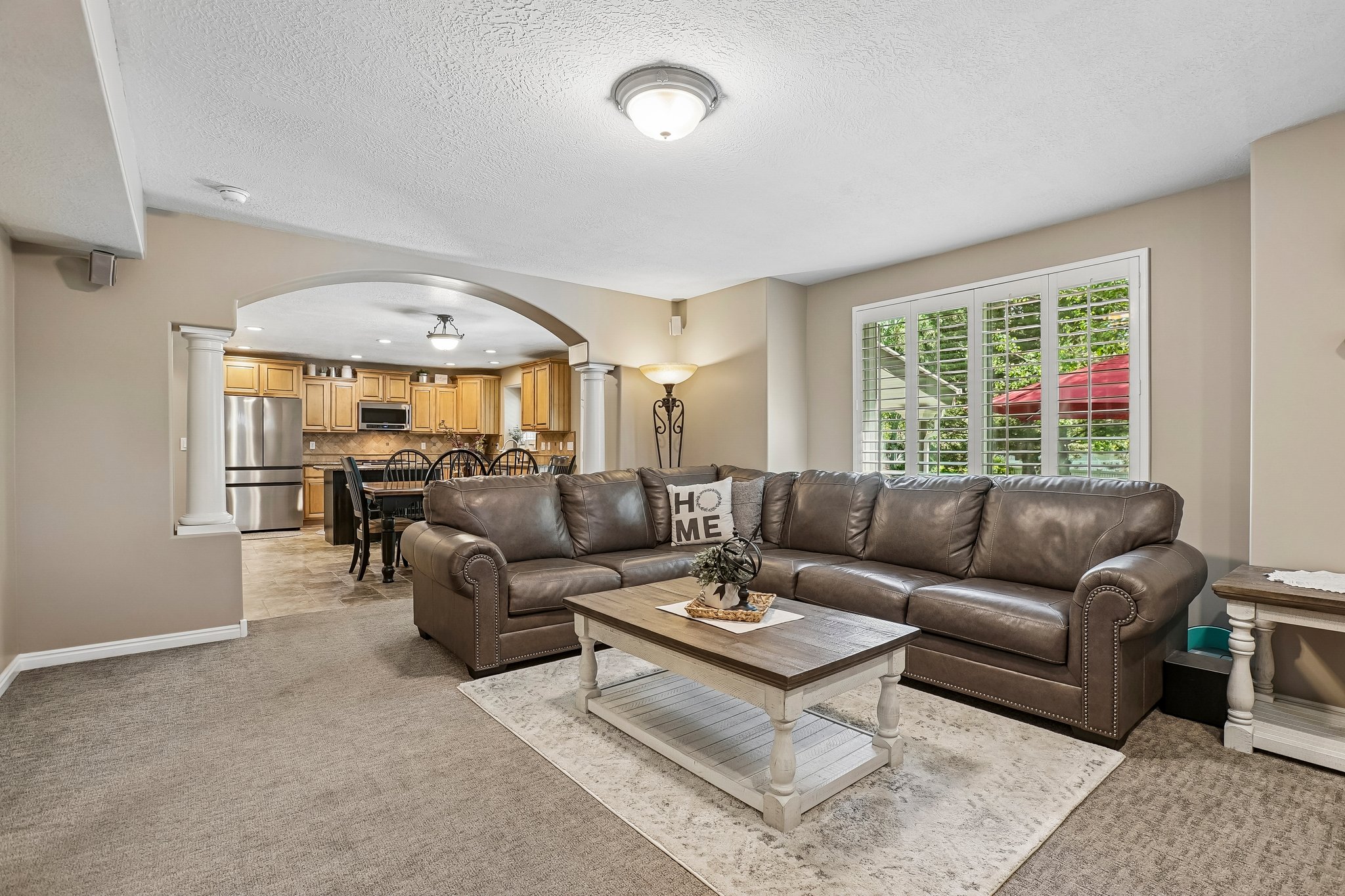Living area featuring carpeted flooring and an arched doorway with decorative columns