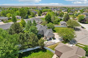 Residential property featuring a grey exterior, dark shingle roof, attached garage, and white fencing