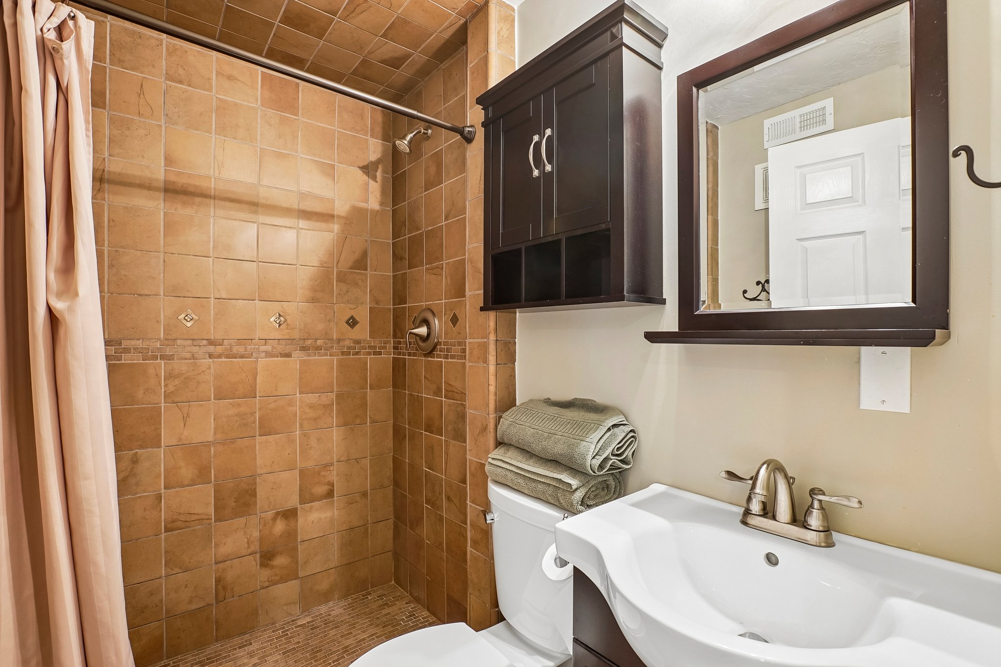 Tiled shower stall with decorative accent band and built-in niche