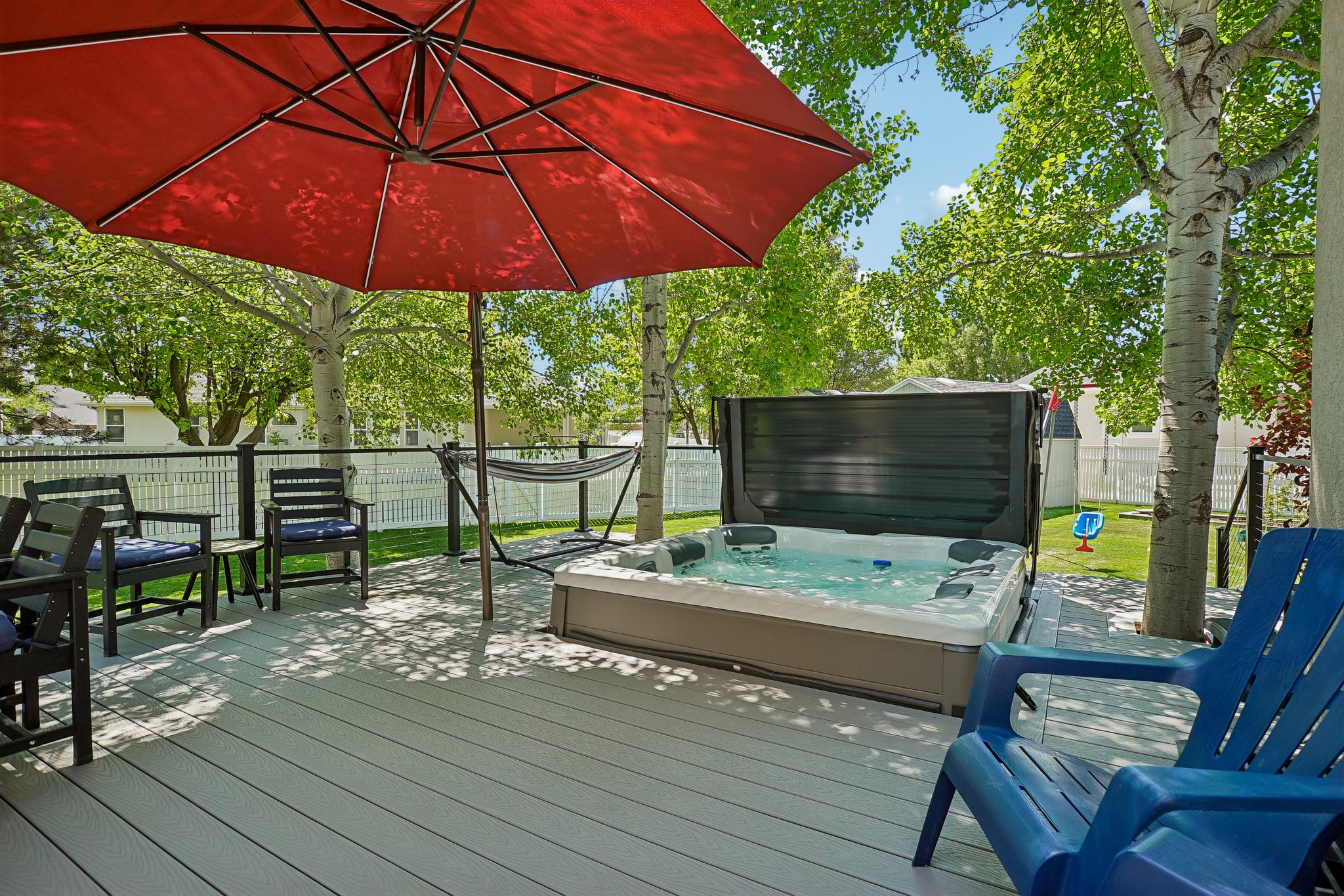 Spacious outdoor deck featuring a built-in hot tub, composite decking, and a black railing system