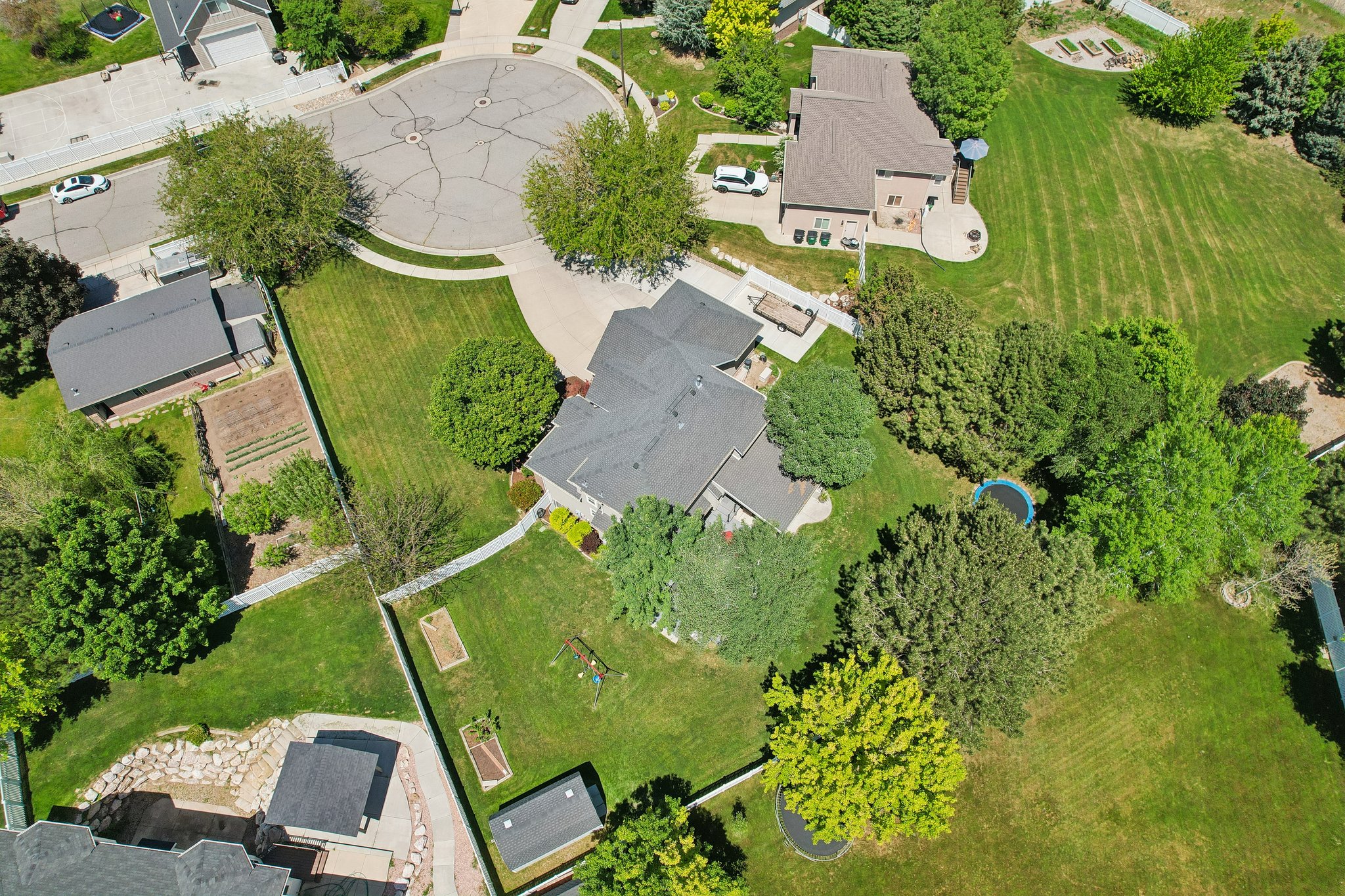 Expansive property featuring a mature tree canopy, manicured lawns, a paved driveway, and an extensive rear patio