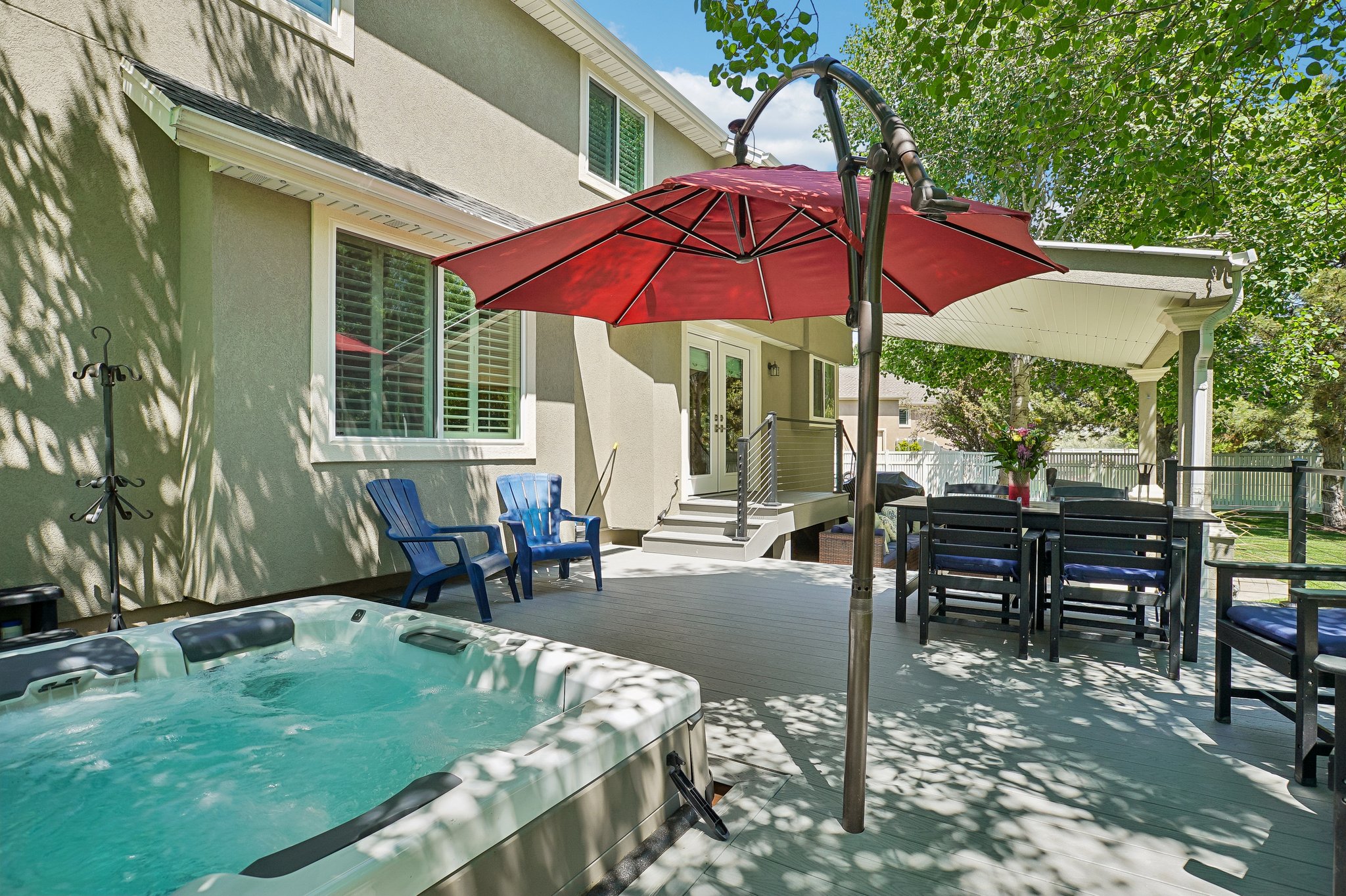 Expansive outdoor deck featuring a built-in hot tub, covered patio area, and exterior double doors