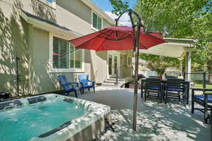 Expansive outdoor deck featuring a built-in hot tub, covered patio area, and exterior double doors