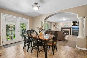 Dining area featuring ceramic tile flooring, French doors with Roman shades, and a ceiling-mounted light fixture