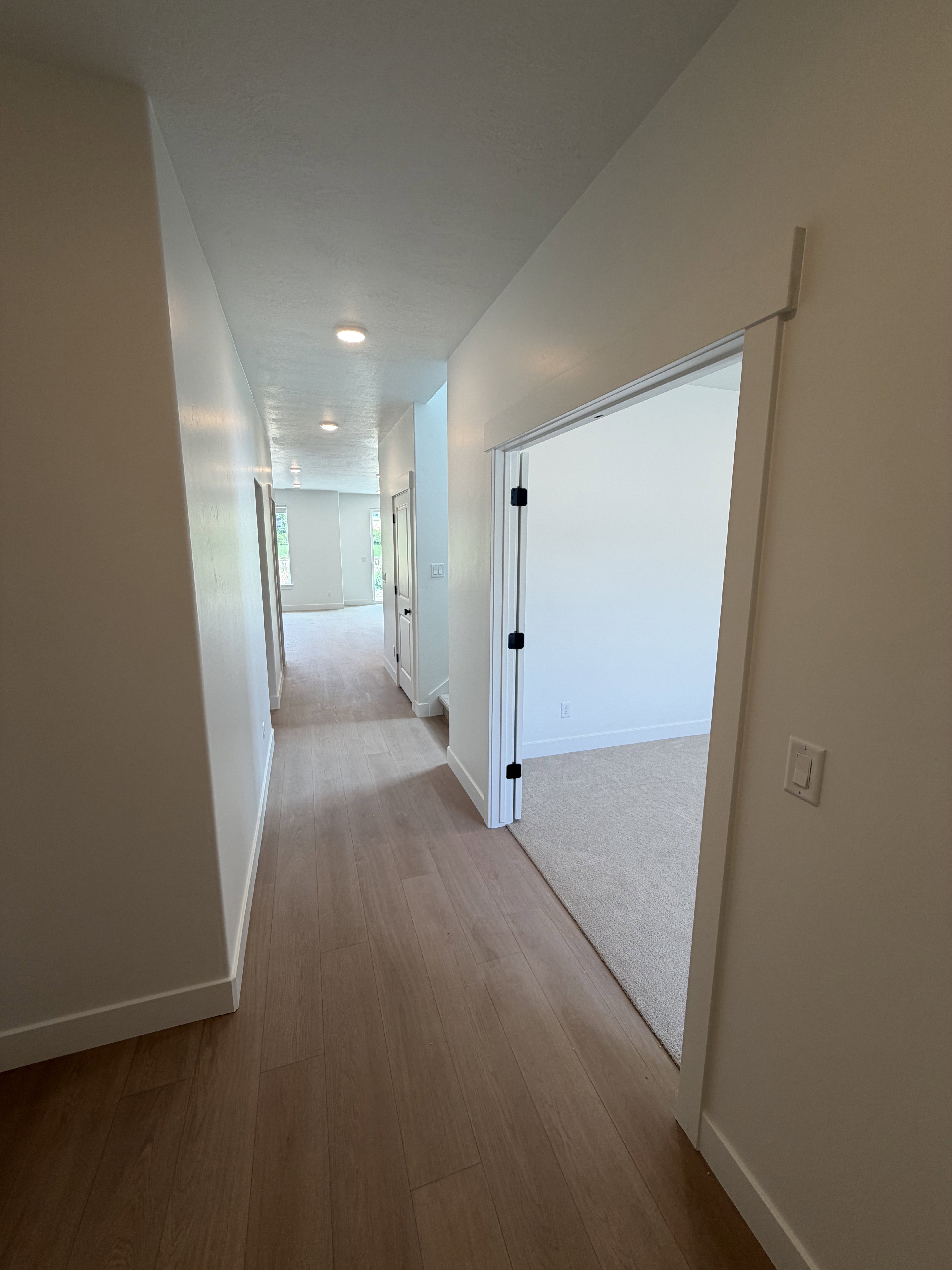 Hallway featuring wood-finish flooring, recessed lighting, and crisp white baseboards
