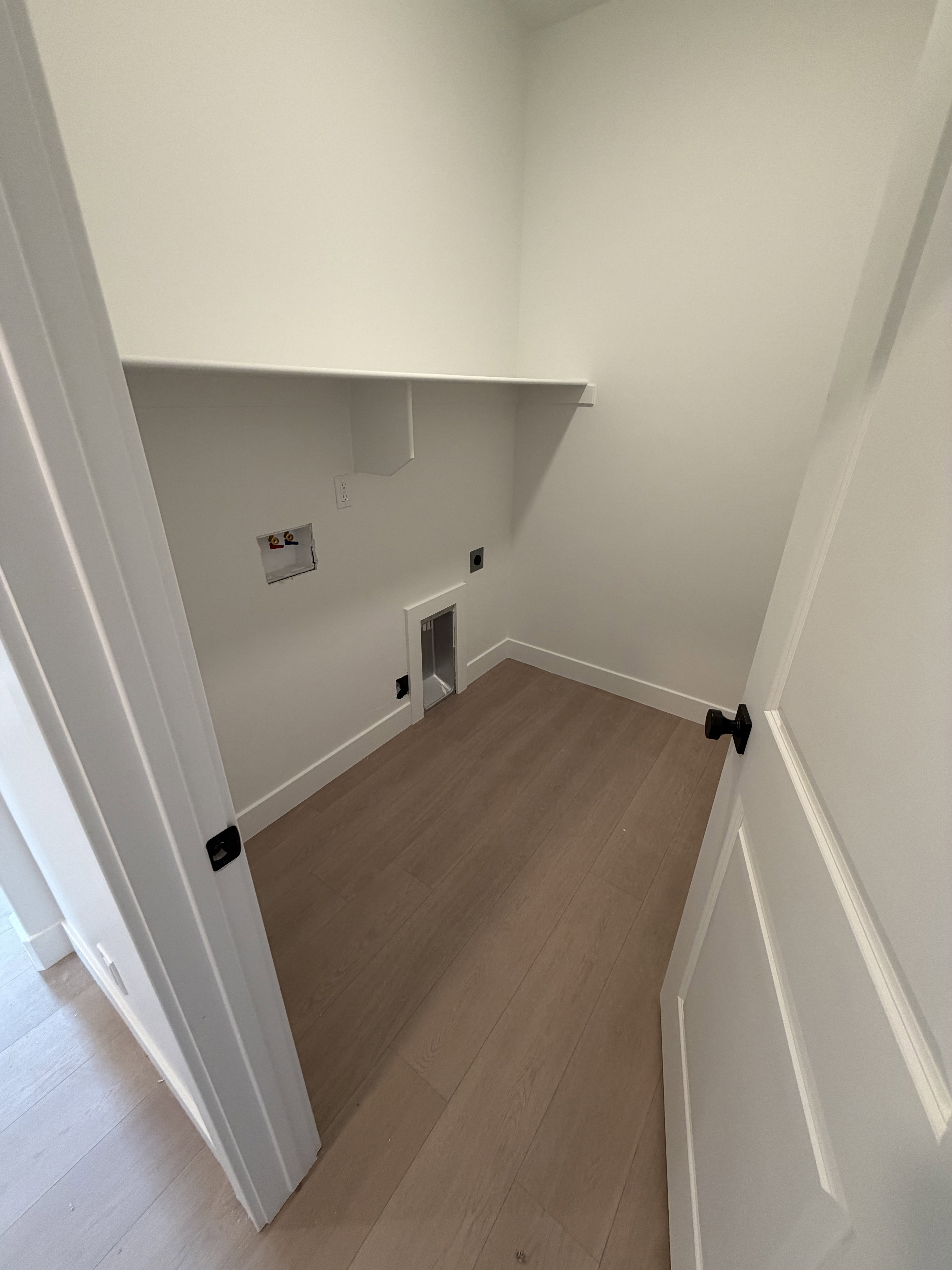 Dedicated utility space featuring light wood-finish flooring and a white built-in shelf