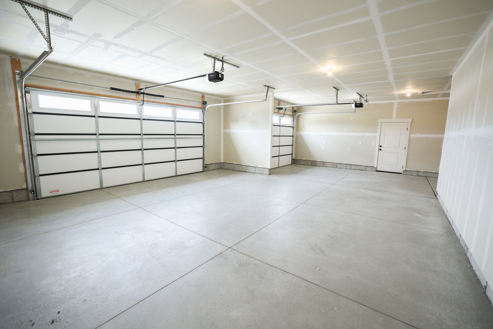 Spacious garage featuring two overhead doors with window accents and automatic openers