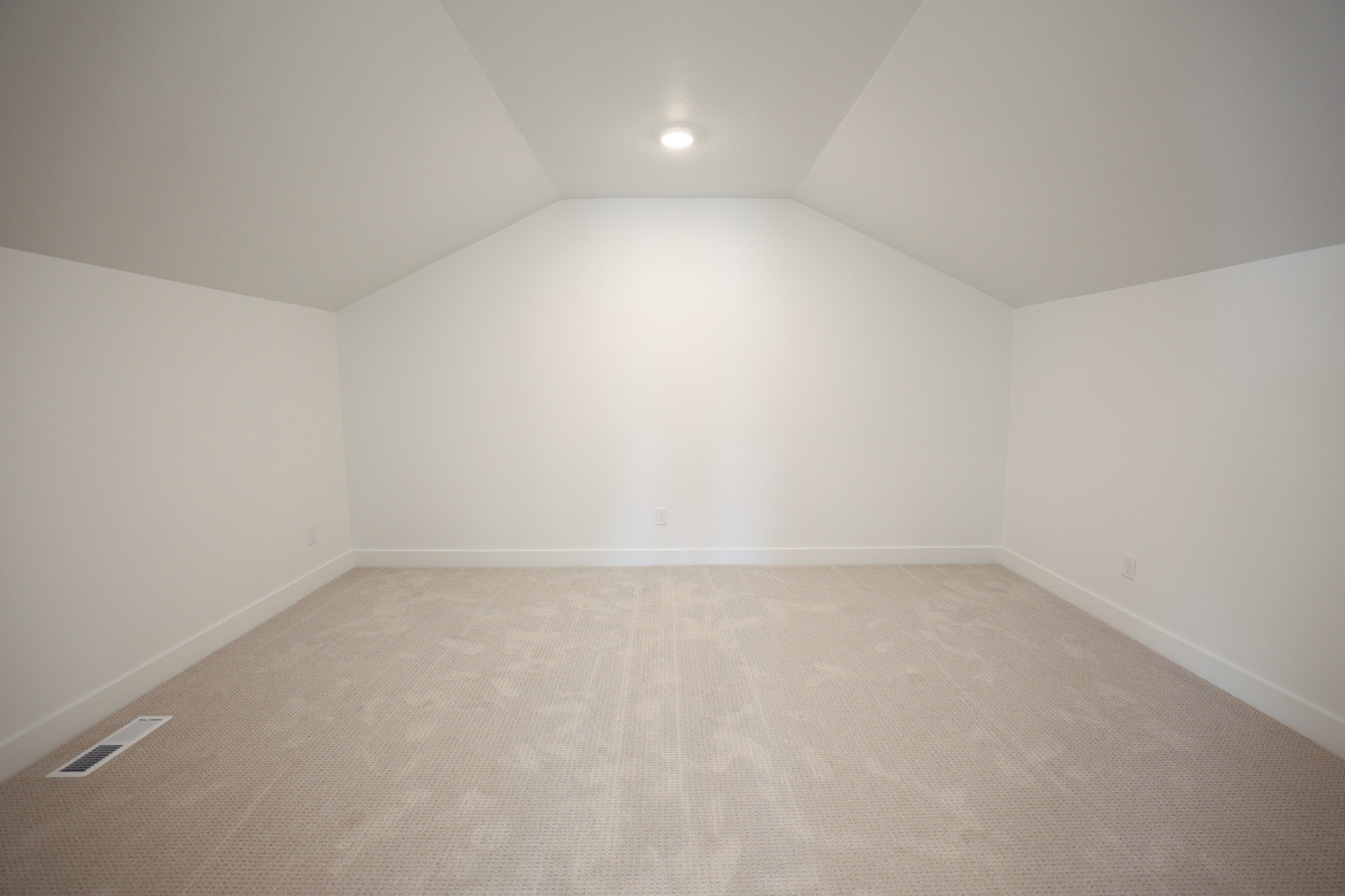 Carpeted room featuring a vaulted ceiling with a recessed light fixture, white walls, and white baseboards