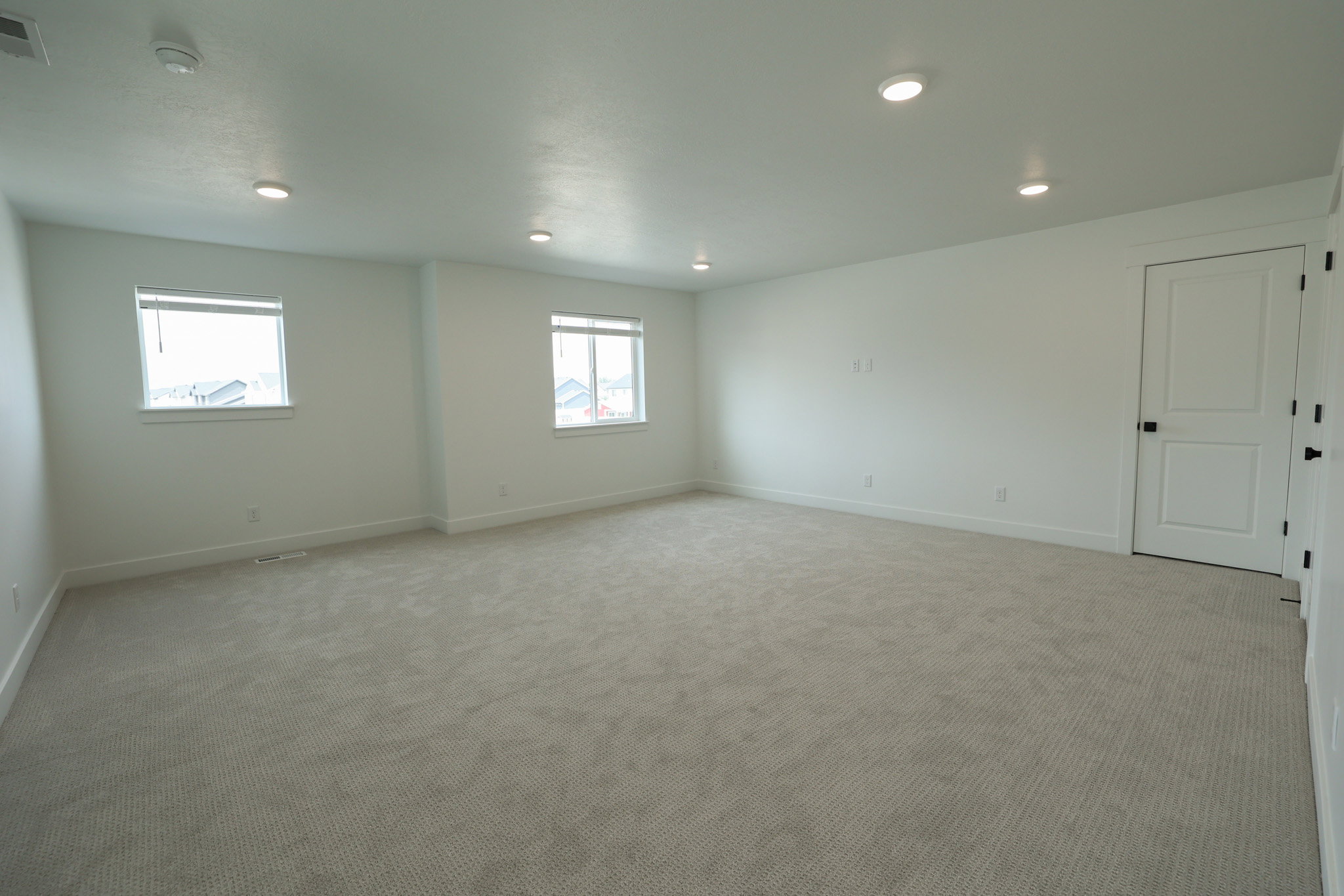 Spacious room featuring neutral carpet flooring, recessed lighting, and white baseboards