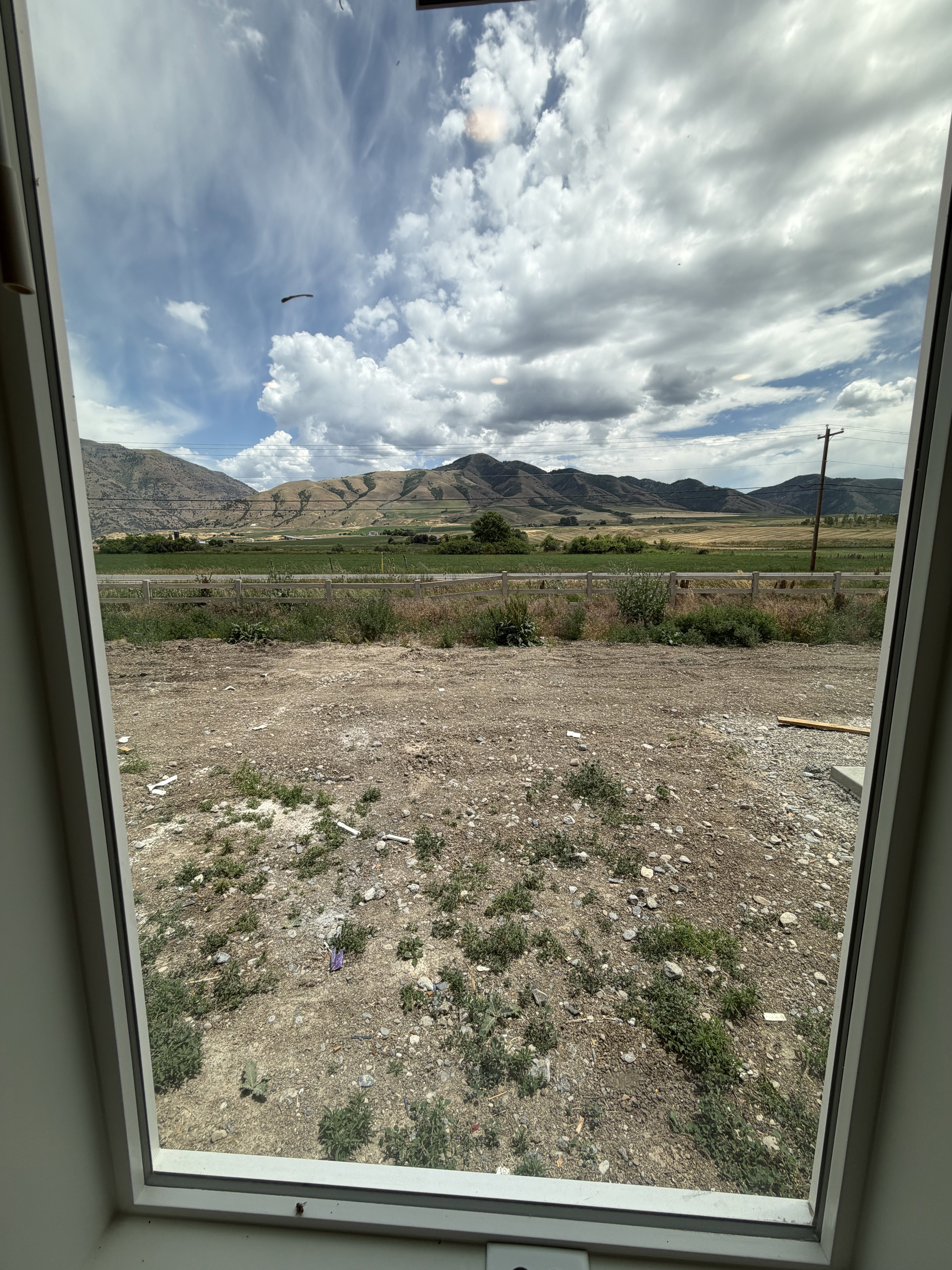 Expansive mountain and field scenery visible through a white-framed window