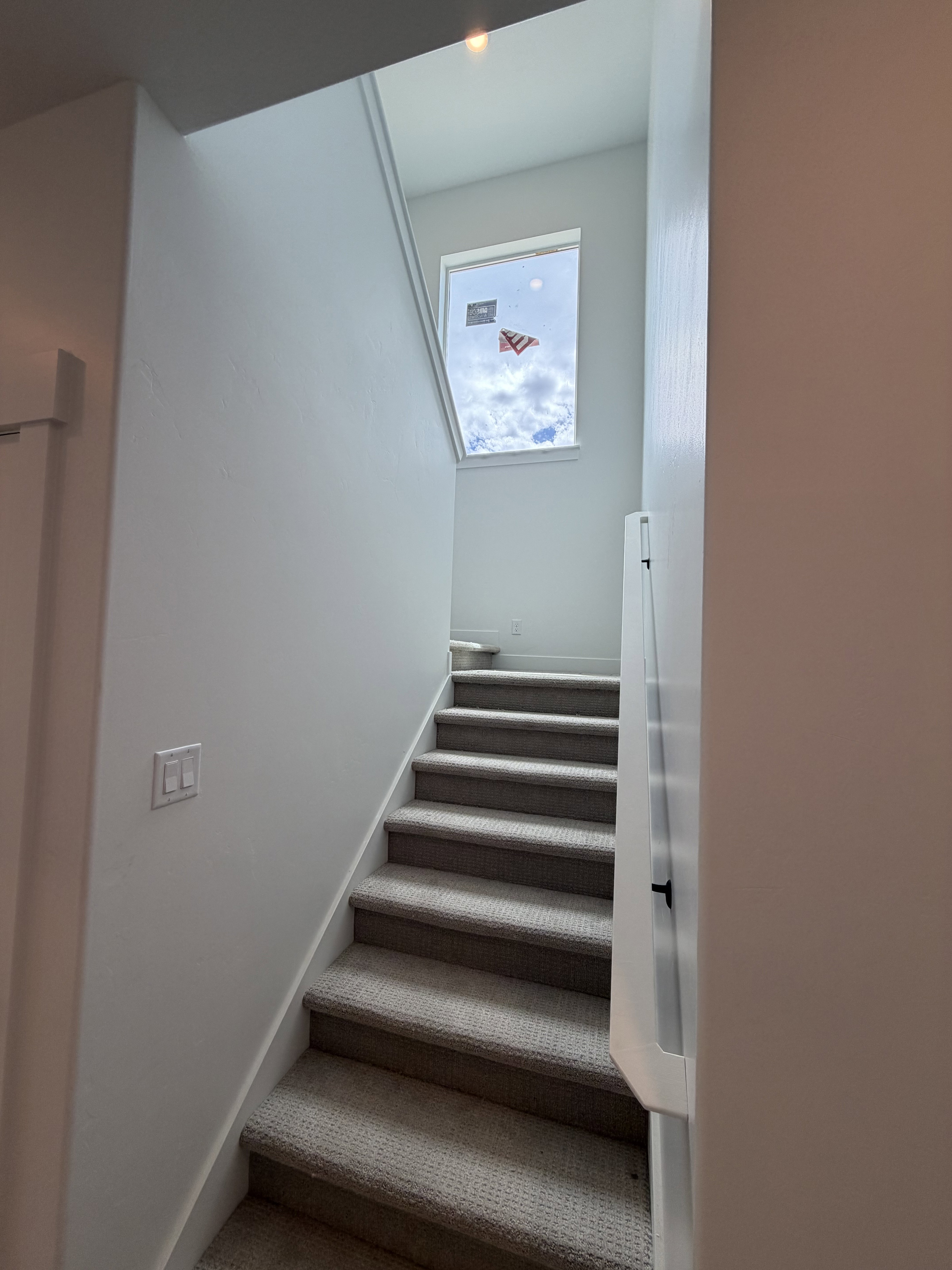 Staircase with light-toned carpeted treads, white risers, and a prominent window