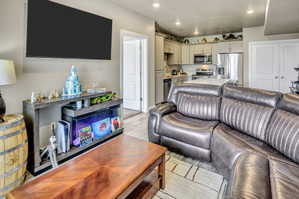 Open-concept living space featuring a kitchen with stainless steel appliances and light-toned cabinetry, an island with a white countertop, and recessed lighting