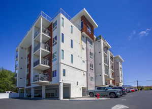 Contemporary multifamily building featuring a white stucco exterior with wood-finish and stone accents