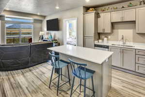 Open-concept living area featuring a kitchen island with seating, wood-finish flooring, recessed lighting, and a sliding glass door