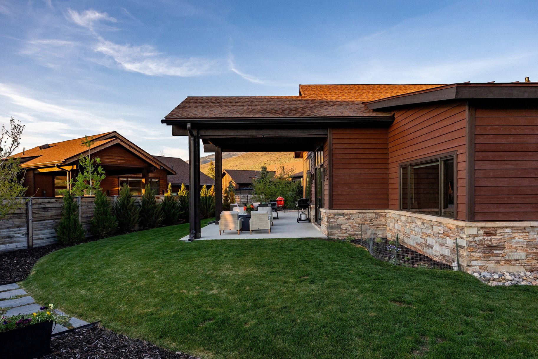 Spacious concrete patio with an attached covered pergola, surrounded by a lush green lawn