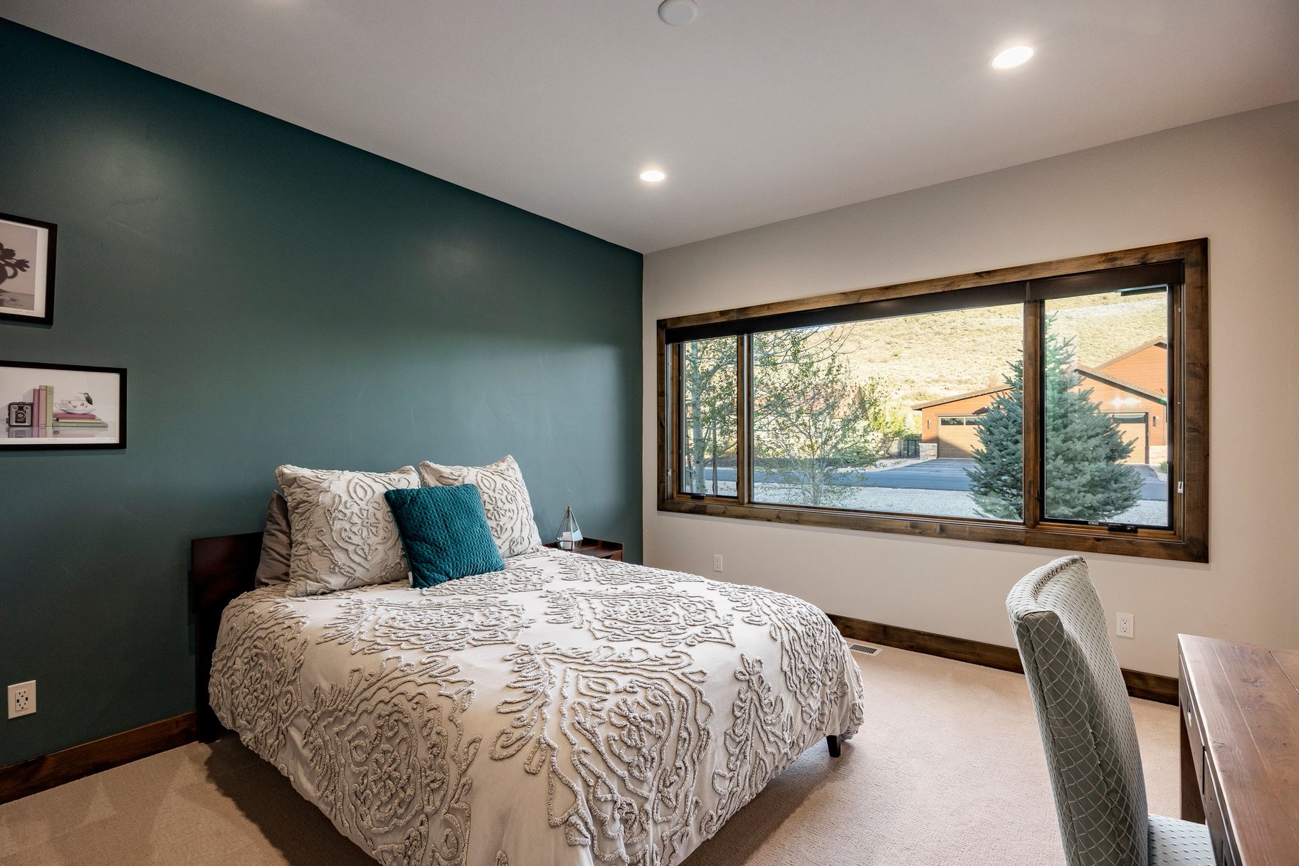 Expansive window framing a natural landscape, recessed ceiling lighting, textured accent wall, light-toned carpeting, and dark wood trim