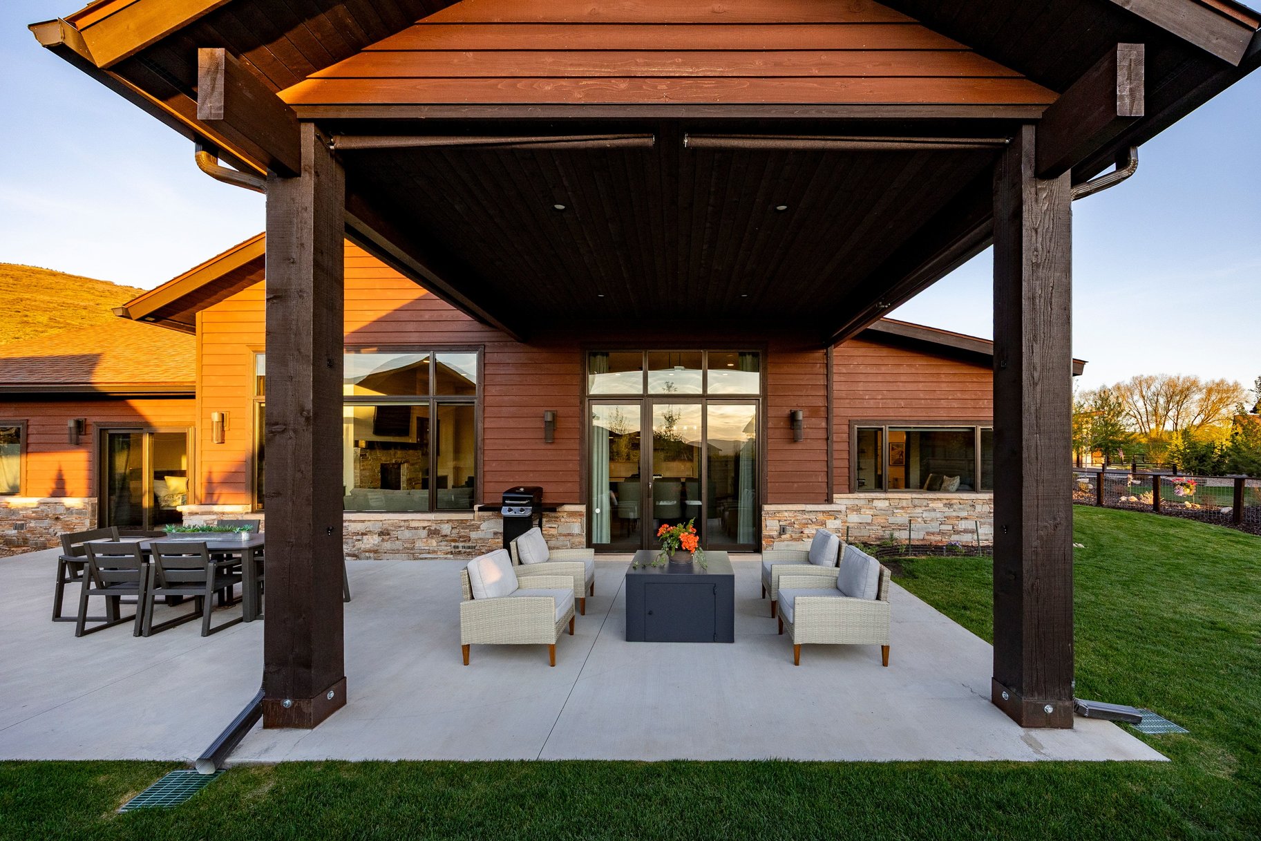 Covered patio featuring an expansive concrete surface, large timber columns, and a rich wood-paneled ceiling