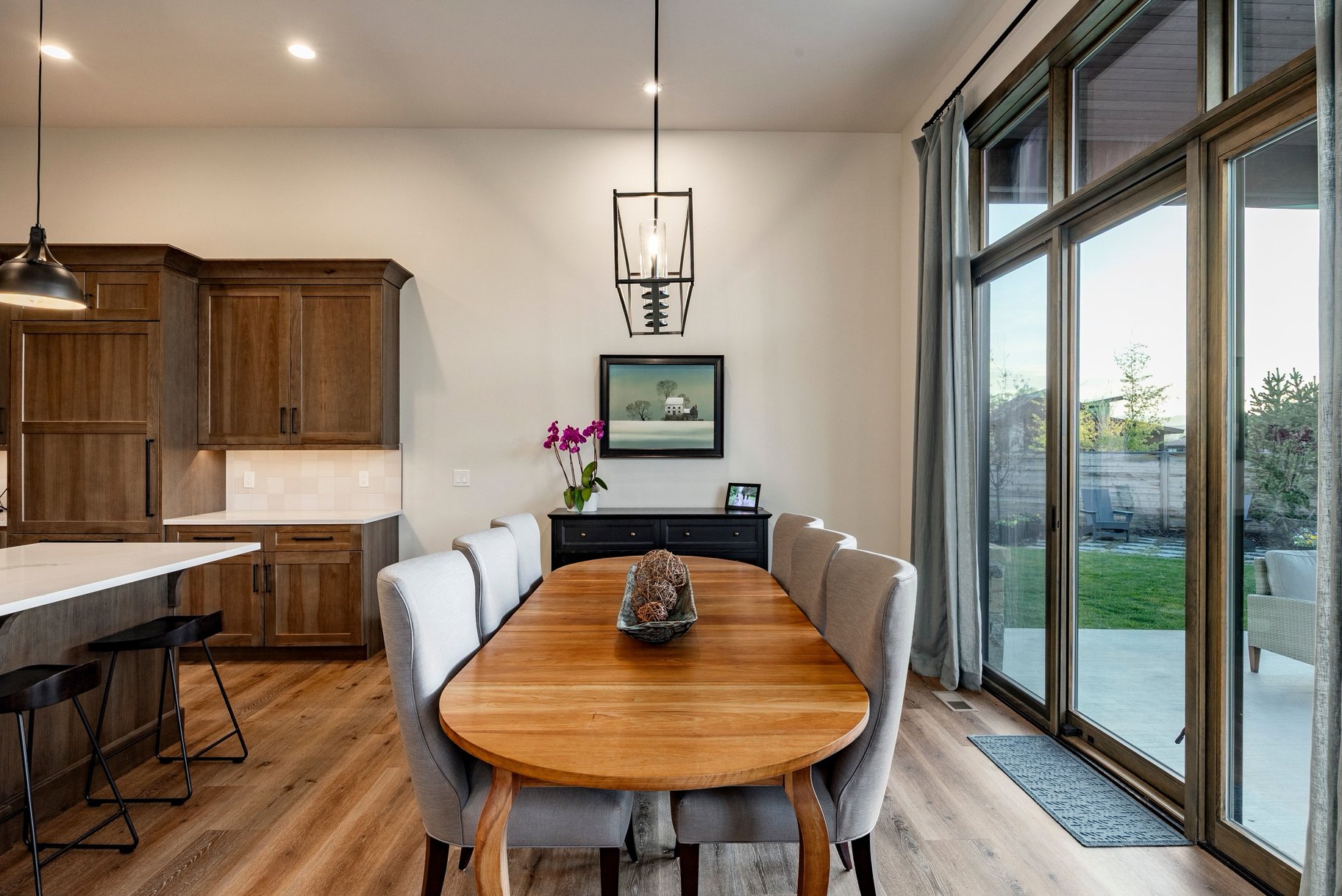 Dining area featuring wood-finish flooring, a contemporary pendant light fixture, and floor-to-ceiling sliding glass doors with transom windows