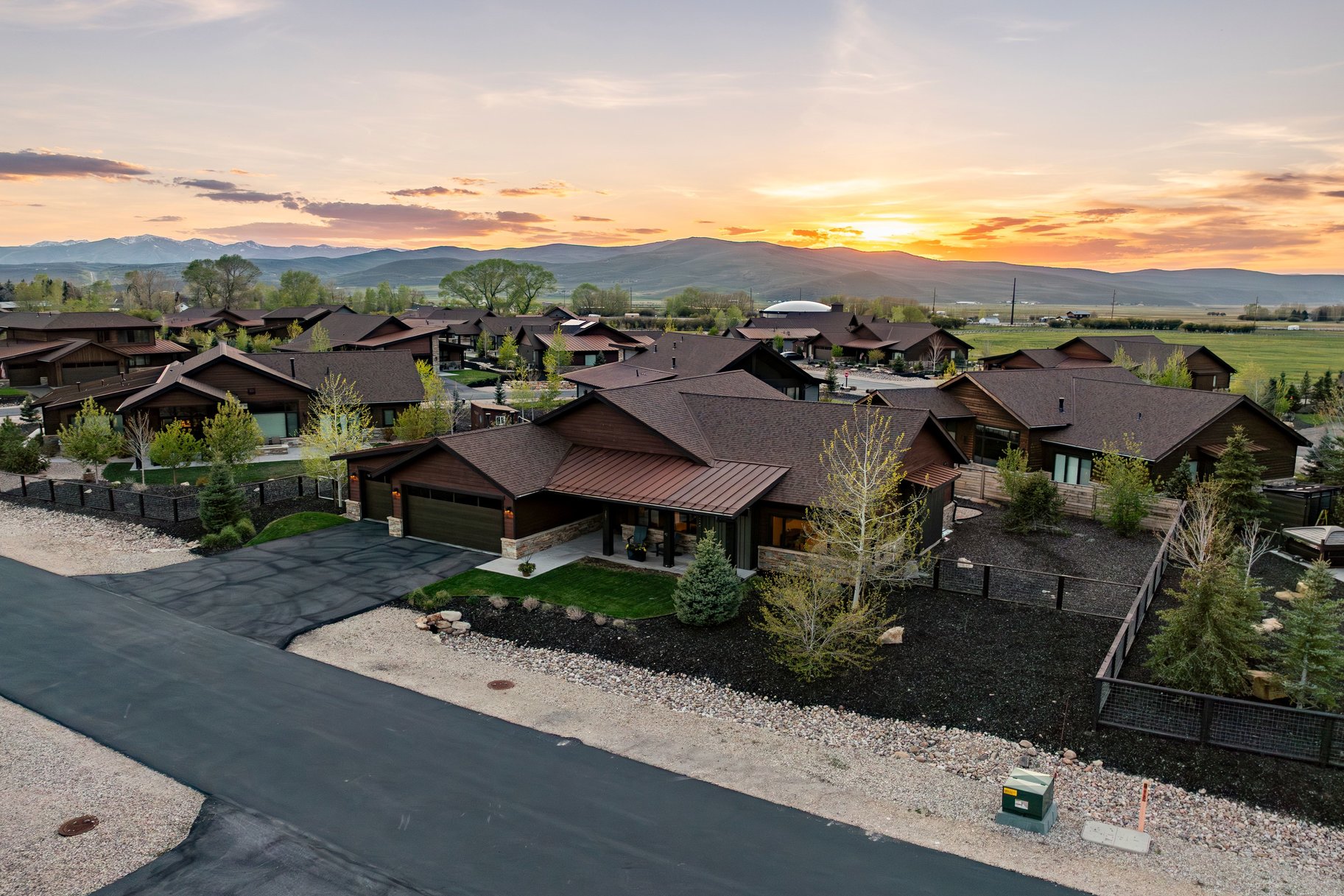Contemporary residential community featuring dark wood-sided homes with brown shingle roofs