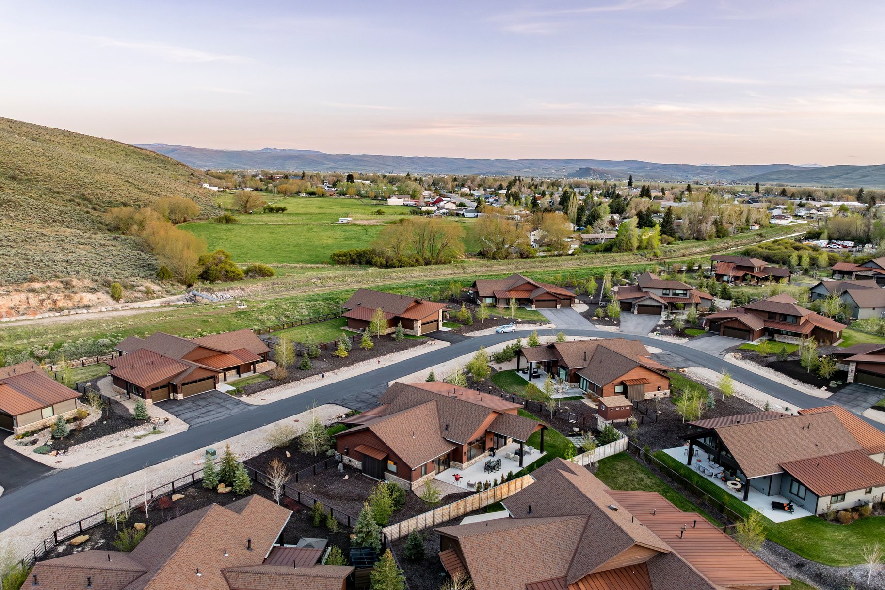 Expansive aerial composition featuring a residential community with contemporary homes, mature landscaping, and paved streets