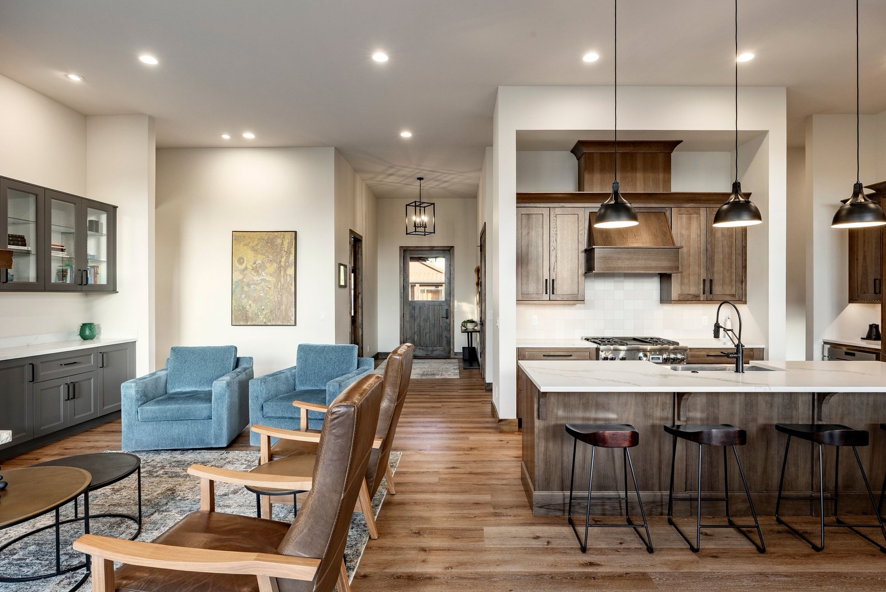 Gourmet kitchen featuring a wood-panel range hood, stainless steel appliances, and a central island with a white countertop and pendant lighting
